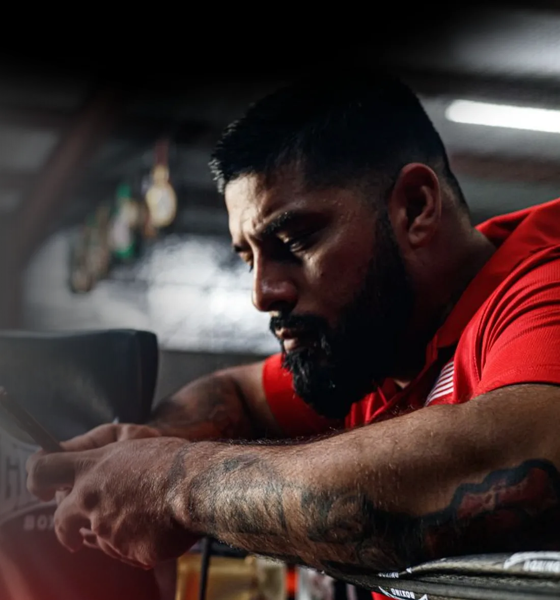 Coach checking FightStable on a phone beside a boxing ring